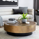 Round wooden coffee table with decorative items in a living room setting.