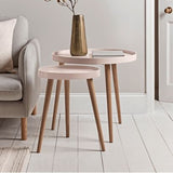 Set of two wooden side tables with a vase of flowers in a living room setting.