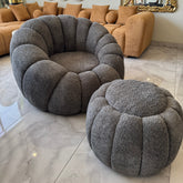 Gray textured armchair and ottoman in a living room setting with a beige sofa and decorative mirrors.