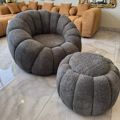 Gray textured armchair and ottoman in a living room setting with a beige sofa and decorative mirrors.