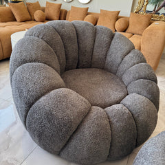 Gray circular cushion in a living room setting with beige sofas and decorative elements.