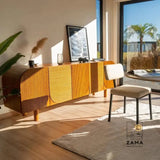 Natural light streams into a modern dining room illuminating a Solstice Fluted Credenza by Zama Home Store, featuring textured wood and curved edges.