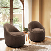 Two brown armchairs in a room with large windows and a plant.