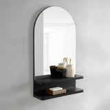 Arched mirror with a black shelf on a white wall
