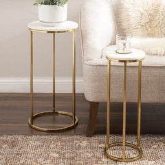 Two gold side tables with marble tops in a living room setting.