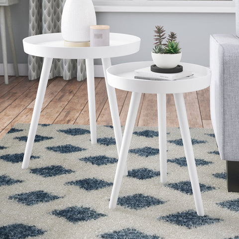 Two white side tables with decorative items on a patterned rug