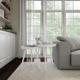 Modern living room with a gray sofa, white coffee table, and large windows.