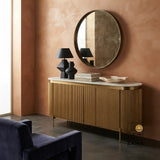 Gold fluted console table with marble top styled with black decor and round mirror.