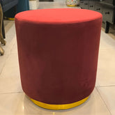 Red round ottoman with yellow base on a tiled floor