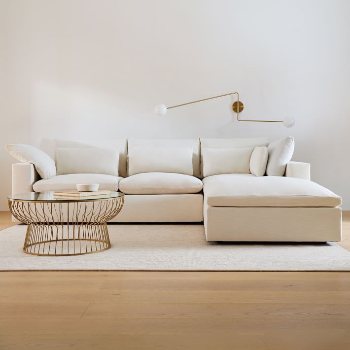 Beige sectional sofa in a modern living room with a coffee table and wall lamp.