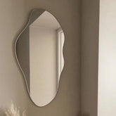 Wavy mirror on a beige wall with a window reflection