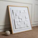 Luxora Grid Wall Art leaning against a wall next to a beige vase, showing the white 3D grid texture.