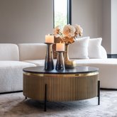 Modern living room with a round coffee table, candles, and flowers.