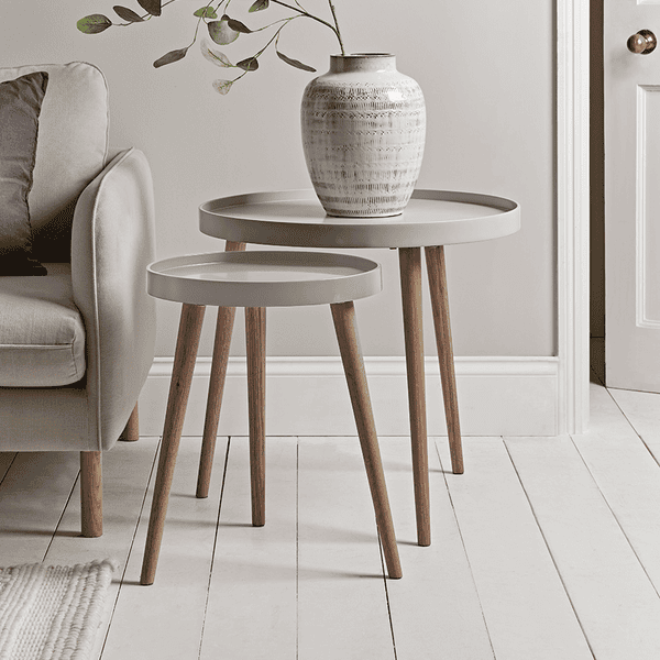 Nest of three tables with a vase and plant in a minimalistic living room.