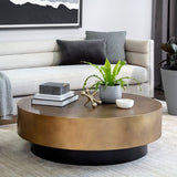 Round wooden coffee table with decorative items in a living room setting.