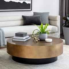 Round wooden coffee table with decorative items in a living room setting.