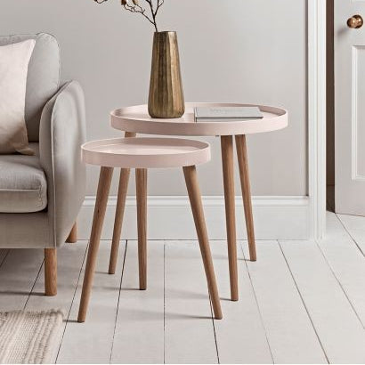 Set of two wooden side tables with a vase of flowers in a living room setting.