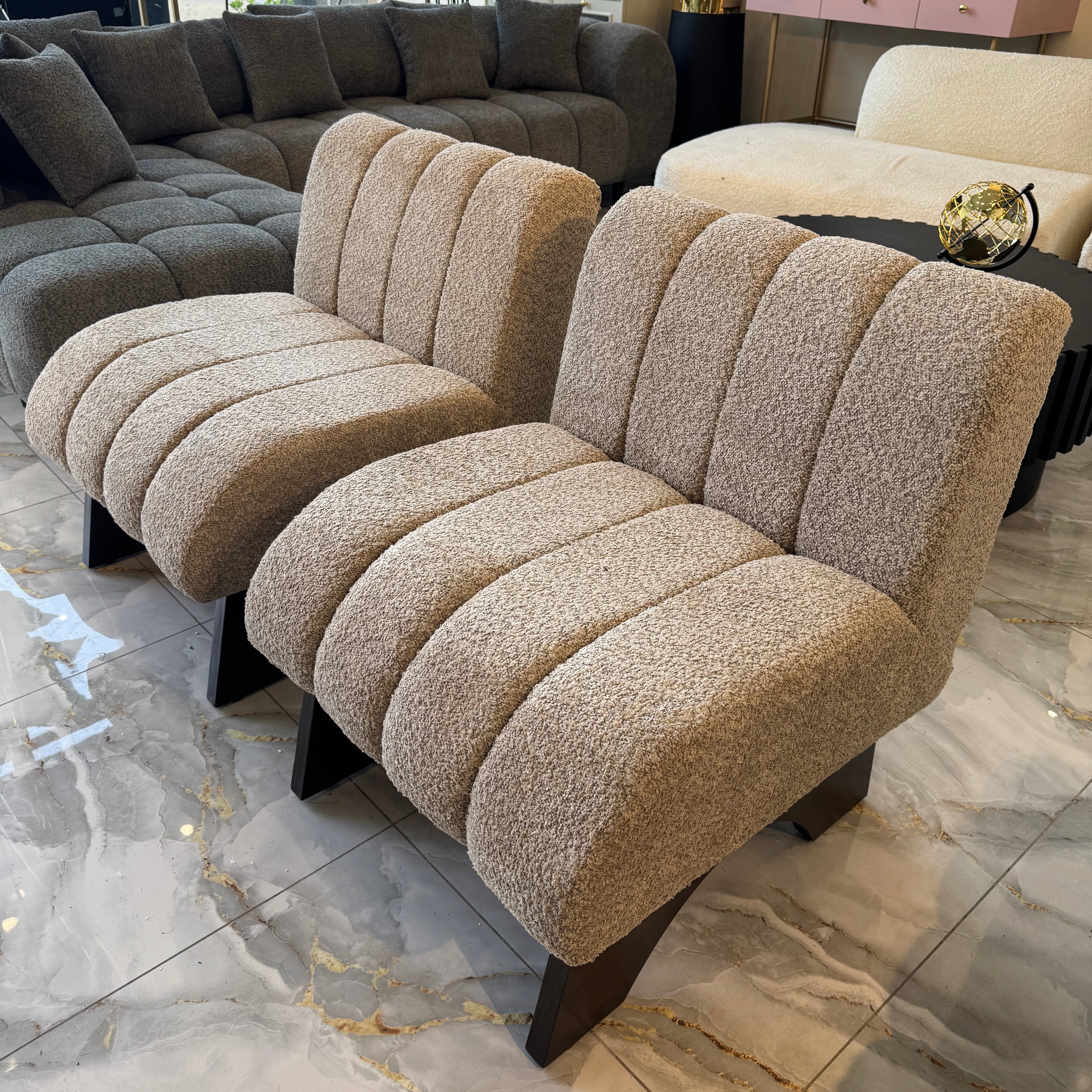 Beige textured sofa in a showroom setting with marble flooring and modern decor.