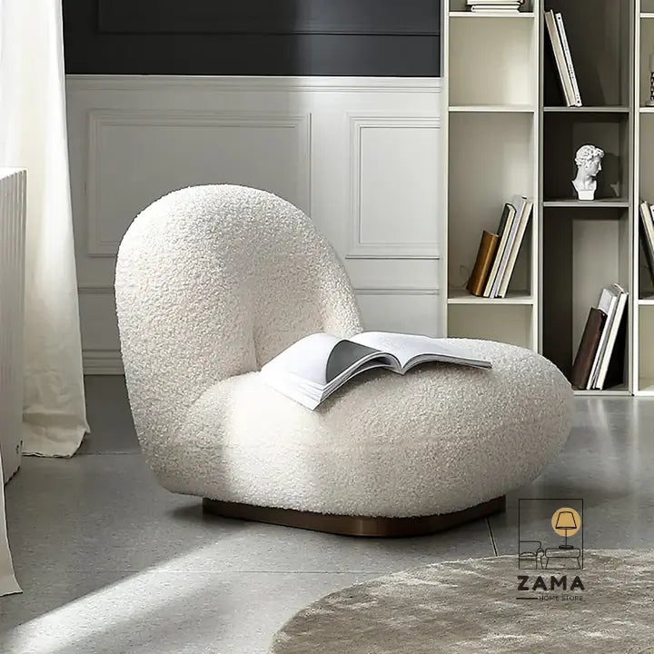 Zama Home Store white bouclé accent chair with an open book resting on the seat, positioned near a modern bookshelf in a bright room.