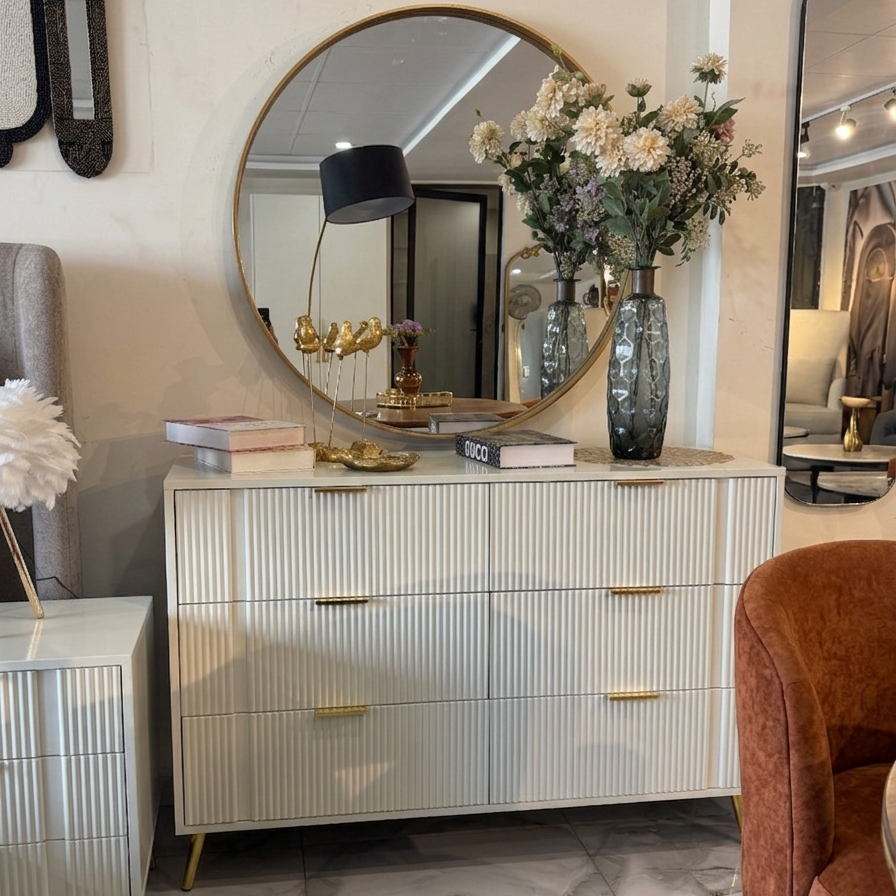 Modern bedroom with a dresser, round mirror, and decorative items.