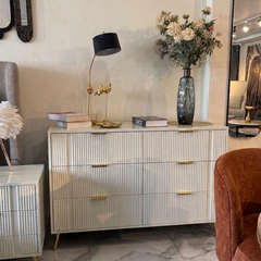 Modern bedroom with a dresser, lamp, and decorative items.