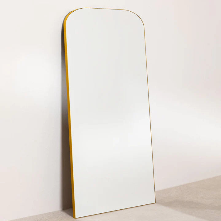 Tall, thin mirror with a gold frame on a white background