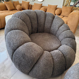 Gray circular cushion in a living room setting with beige sofas and decorative elements.