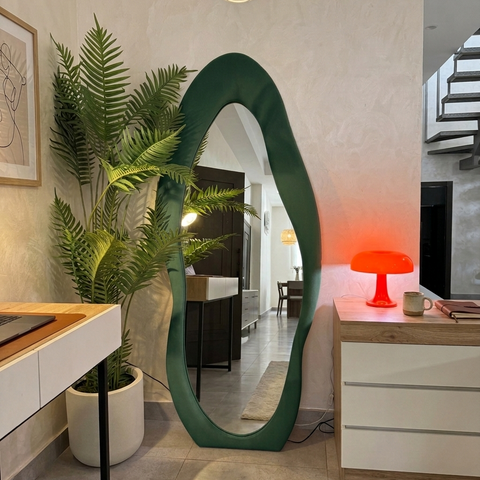 Modern interior with a green oval mirror, potted plant, and desk.