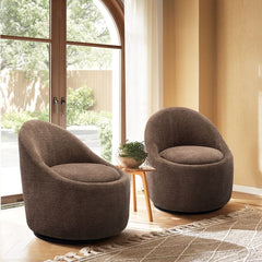 Two brown armchairs in a room with large windows and a plant.