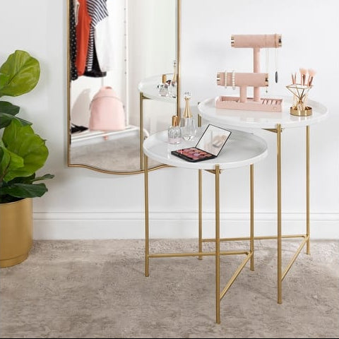 Small round marble table with gold legs in a room setting.