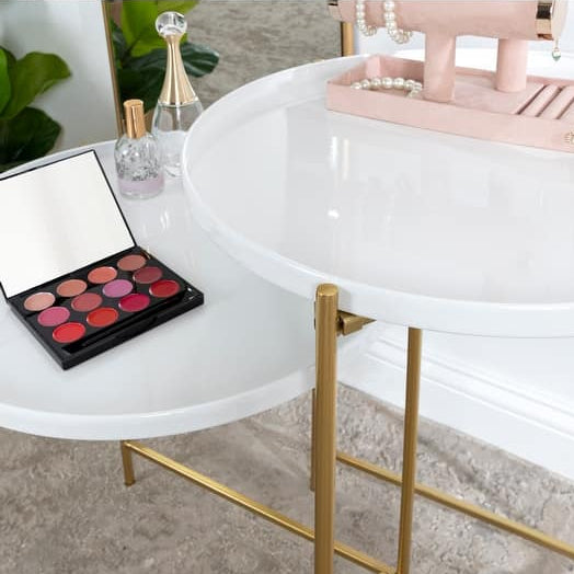 Makeup palette on a white round table with gold legs, surrounded by jewelry and decor.