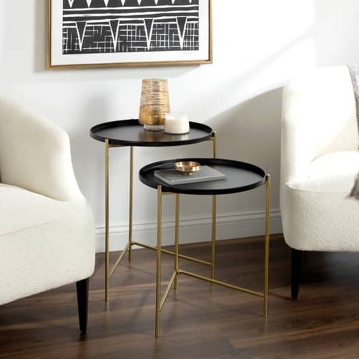 Modern side table with black top and gold legs in a living room setting.
