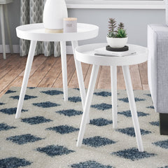 Two white side tables with decorative items on a patterned rug