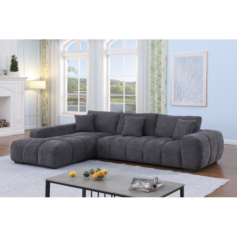 Gray sectional sofa in a living room with large windows and a fireplace.