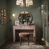 Pink modern makeup vanity with a circular mirror and matching stool in a luxury green walk-in closet.