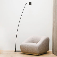 Modern floor lamp and armchair in a minimalistic room with a neutral color palette.