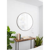 Round mirror on a white wall above a wooden console table with decorative items.
