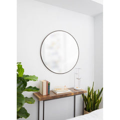 Round mirror on a white wall above a wooden console table with decorative items.