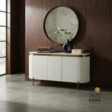 White fluted credenza with brass accents placed against a warm wood panel wall.