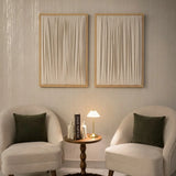 ETOFFE Wall Art set with cream draped fabric in light wood frames hanging above chairs.