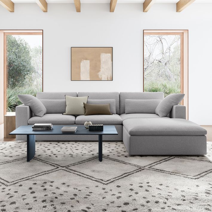 Gray sectional sofa in a modern living room with abstract art and large windows.