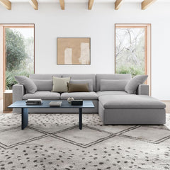 Gray sectional sofa in a modern living room with abstract art and large windows.