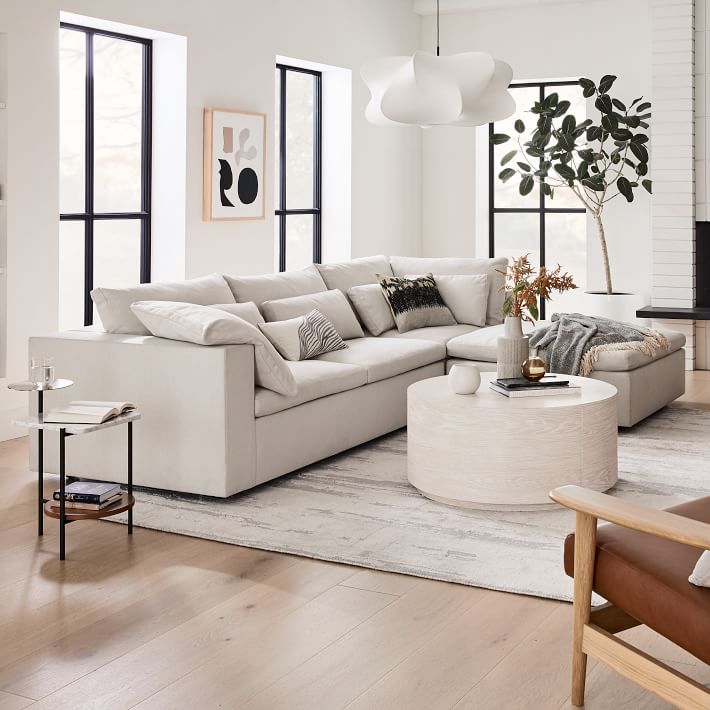 Modern living room with a beige sectional sofa, white coffee table, and decorative elements.