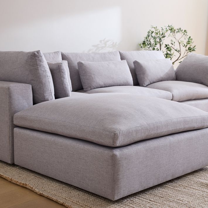 Gray sectional sofa in a living room setting with a plant in the background.