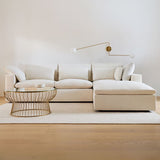 Beige sectional sofa in a modern living room with a coffee table and wall lamp.