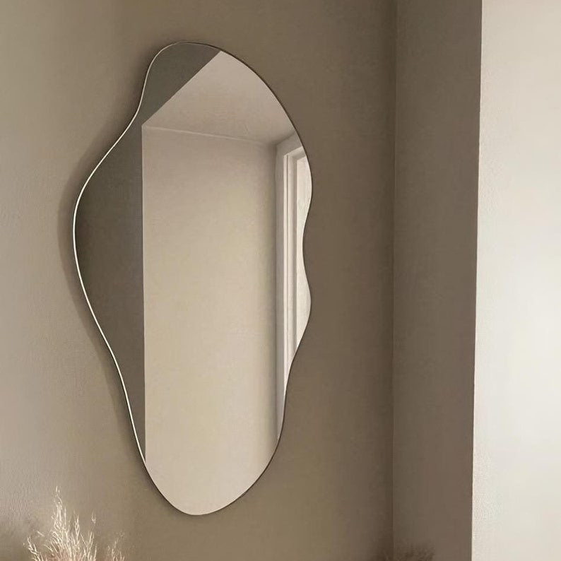 Wavy mirror on a beige wall with a window reflection