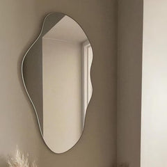 Wavy mirror on a beige wall with a window reflection