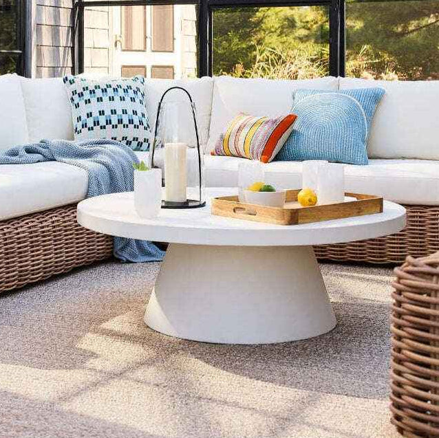 Outdoor patio setting with a white sofa, wicker chairs, and a round coffee table.