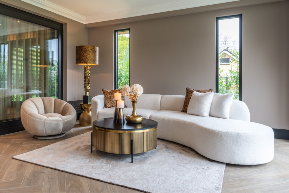 Modern living room with a white sectional sofa, round coffee table, and decorative items.