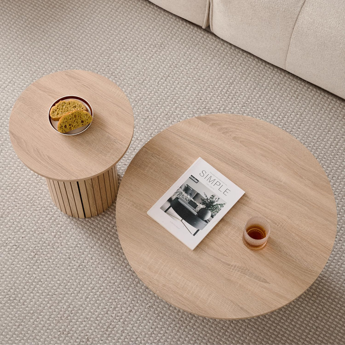 Two wooden coffee tables with a magazine and small items on a textured floor.